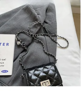 Detail of glossy black quilted mini bag with silver metal turn-lock and chain strap