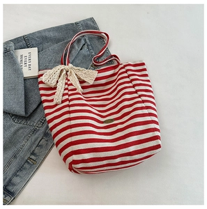 Detailed close-up of red and white striped canvas tote bag with a beige lace bow