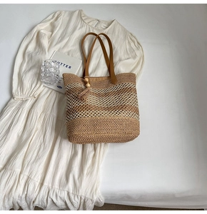 Detail of woven straw tote bag with brown leather straps and tassel on white dress