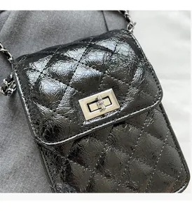 Detail of black quilted chain phone bag with silver twist lock and glossy finish