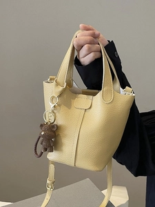 Stylish yellow bucket handbag in lychee texture leather with a cute bear charm accessory