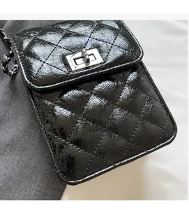 Detail of black quilted leather shoulder bag with silver turn-lock and chain strap