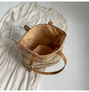 Detail of straw tote bag interior with zipper closure, lining, and leather straps