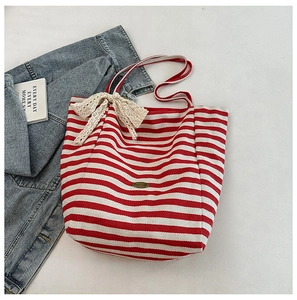 Detail of red and white striped canvas tote bag with a beige lace bow and handmade logo