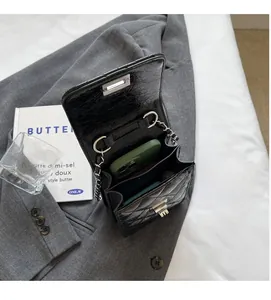 Internal view of black crocodile texture chain bag holding a green smartphone
