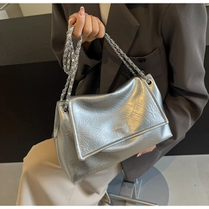 Detail shot of the silver crinkled leather texture and metal chain strap of the shoulder bag
