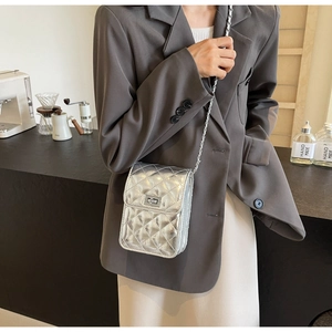 Detailed view of silver quilted crossbody bag with metal chain strap and twist lock