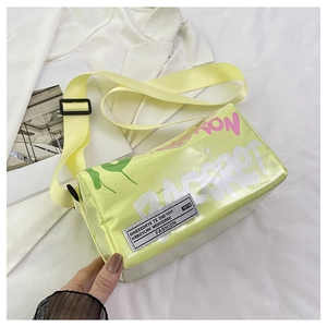 Detail of light yellow jelly crossbody bag featuring pink graffiti and wide nylon strap