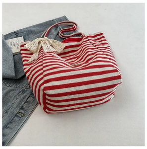 Detail of red striped canvas tote bag featuring a white lace bow and spacious interior