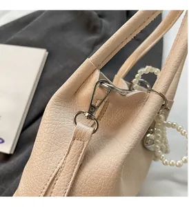 Détail du sac à main beige clair en cuir grainé avec crochet argenté et perles