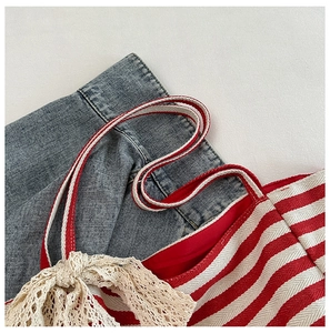 Macro detail of red white striped canvas bag with elegant beige lace and braided handles