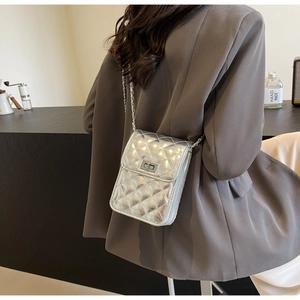 Silver quilted crossbody bag with metal twist lock and chain strap worn by a model