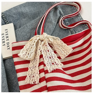 Detailed macro of red and white striped canvas tote bag with cream lace bow and red lining