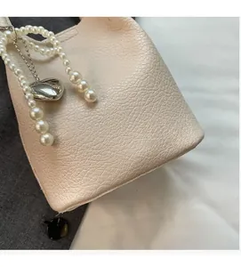 Gros plan sur un sac cabas en cuir beige grainé avec bandoulière en perles et cœur