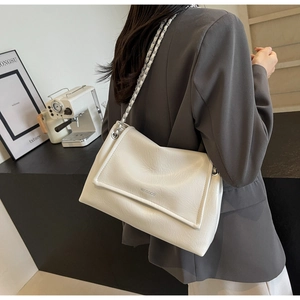 Detail of a beige leather shoulder bag with a chain strap and woven leather texture