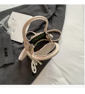 Détail du mini sac cabas crème avec poche zippée et pendentif perle élégant