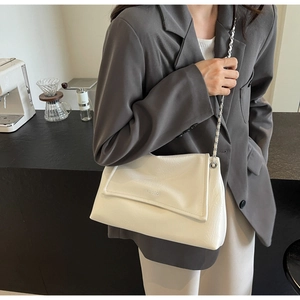 Close-up of white textured leather shoulder bag with silver chain and metal brand logo