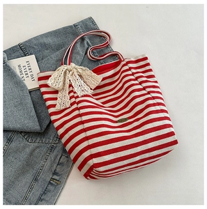 Detail of red striped canvas tote bag with decorative lace bow and brand plaque