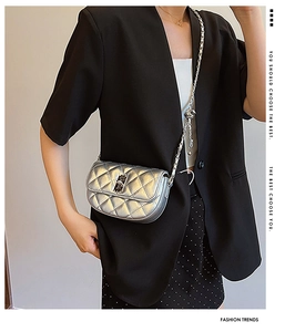 Detailed close-up of a silver metallic quilted saddle bag with a woven chain strap