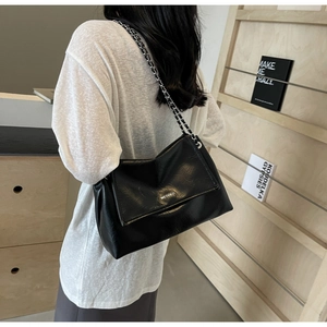 Detail of black leather chain bag with WEGOGO logo on textured leather surface