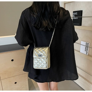 Detail shot of a golden quilted crossbody mini bag with elegant chain strap worn by a model