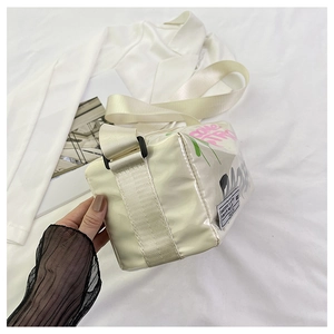 Detailed macro of white graffiti square bag with wide fabric strap and buckles