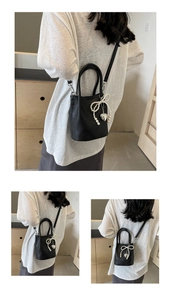 Détail du sac seau en cuir noir grainé avec nœud en perles et pendentif cœur argenté