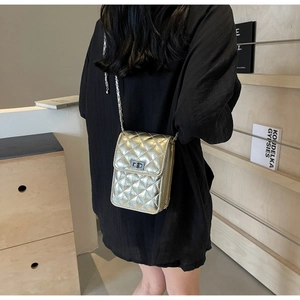 Detail of silver quilted crossbody bag featuring metal turn-lock and chain strap
