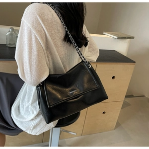 Detail of the high-quality black crinkle faux leather texture and leather chain strap on shoulder bag
