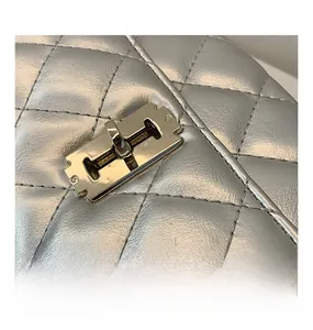 Macro shot of the polished gold metal lock on a silver quilted leather saddle bag