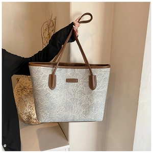 Detail of grey marble texture and brown leather trim on a large capacity tote bag