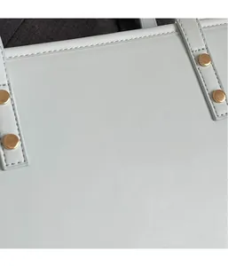 Detailed macro view of light blue tote bag showing premium stitching and gold hardware studs