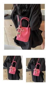 Détail du sac seau rose fuchsia avec nœud en perles et pendentif cœur argent