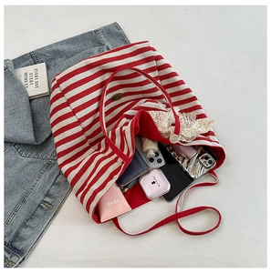 Detail view of large canvas tote bag with red stripes and lace bow decoration