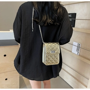 Detail of silver quilted crossbody bag with metallic chain strap and twist lock closure