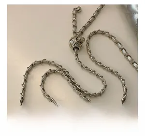 Detail of silver metal chain strap with woven leather and adjustable diamond quilted bead