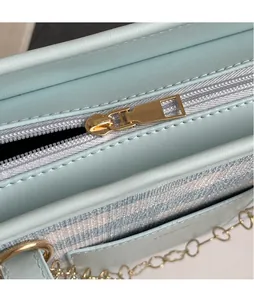 Close-up of golden zipper on striped tote bag with light blue leather trim detail