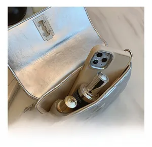 Detailed interior capacity of silver quilted chain saddle bag with daily essentials