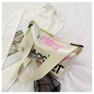 Detail of graffiti-style cream crossbody bag with a wide nylon strap and glossy finish
