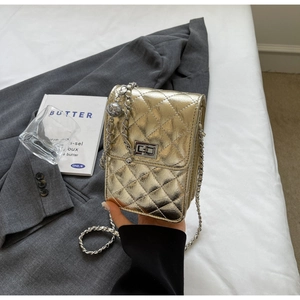 Detail of gold quilted crossbody bag with metallic chain and elegant twist-lock closure