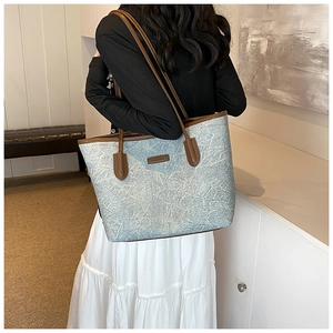 Detail of light blue tote bag with brown leather straps and textured surface