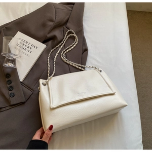 Detail view of white wrinkled leather texture and silver chain strap on shoulder bag