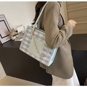 Detail of blue and white checkered tote bag with gold floral chain and leather pocket