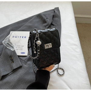 Detail of black quilted leather mini bag with silver metal turn-lock and chain strap