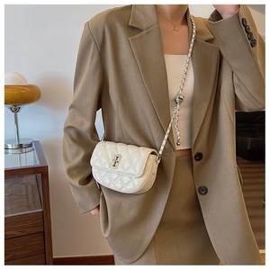 Close-up of white quilted crossbody bag with metal chain strap and ball adjuster