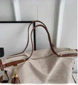 Detailed close-up of woven canvas texture with brown leather handles and gold rivets