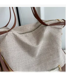 Detailed close-up of beige woven fabric texture and premium brown leather handle with gold zipper