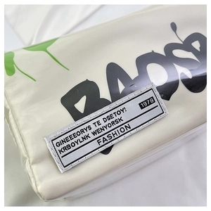 Detail of waterproof PVC bag showing green spray art and embroidered fashion label