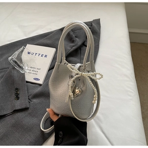 Vue détaillée du sac seau argenté à texture litchi avec nœud en perles et cœur