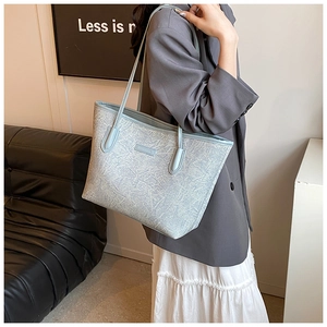 Detail of light blue textured tote bag styled with gray blazer for professional commute